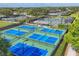 Aerial view of multiple pickleball courts with blue and green surfaces, surrounded by lush landscaping at 2518 Dick Wilson Dr, Sarasota, FL 34240