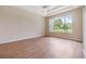 Spacious bedroom with wood floors, a tray ceiling, and a large window overlooking the backyard at 27427 Mistflower Dr, Wesley Chapel, FL 33544