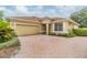 Inviting single-story home featuring a two-car garage and a brick-paved driveway at 27427 Mistflower Dr, Wesley Chapel, FL 33544