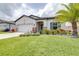 Well-maintained front yard with lush lawn, colorful landscaping, and a palm tree, enhancing the curb appeal of the home at 30762 Parrot Reef Ct, Wesley Chapel, FL 33545