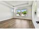 Minimalist bedroom with tray ceiling, wood flooring, white walls, and bright windows showcasing a serene backyard view at 3110 19Th N St, St Petersburg, FL 33713