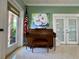 This piano is ready for musical performances, with a decorative wall, a window to the exterior, and a patriotic flag at 3301 Alt 19 # 819, Palm Harbor, FL 34683