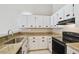 Updated kitchen boasting granite countertops, white cabinets, and black appliances at 3389 Crystal E Ct # J, Palm Harbor, FL 34685