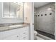 Granite vanity and grey tiled shower in updated bathroom at 340 Causeway Blvd # 105, Dunedin, FL 34698