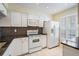 Updated kitchen features white appliances, mosaic backsplash, and ample cabinet space for organized storage at 340 Causeway Blvd # 105, Dunedin, FL 34698