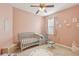 Charming Bedroom featuring a gray crib, ceiling fan, area rug, and neutral pink walls at 34447 Windknob Ct, Wesley Chapel, FL 33545