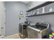 Laundry room with modern washer and dryer units, floating shelves, and stylish decor at 34447 Windknob Ct, Wesley Chapel, FL 33545