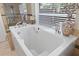 Close up of soaking tub with window and decorative vase in a neutral tiled bathroom at 4047 Eagle Cove West Dr, Palm Harbor, FL 34685