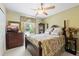 Cozy bedroom featuring wooden furniture, floral bedding, a ceiling fan and natural light at 4047 Eagle Cove West Dr, Palm Harbor, FL 34685
