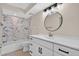 Well-lit bathroom with a modern vanity, round mirror, and bathtub with decorative tiled wall at 431 Windward Psge, Clearwater Beach, FL 33767