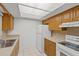 Well-lit kitchen featuring white appliances, wood cabinets, and a stainless steel sink at 4500 E Bay Dr # 106, Clearwater, FL 33764