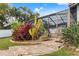 Landscaped backyard featuring a screened-in porch, lush plantings, and stepping stone pavers at 4931 Pelican Dr, New Port Richey, FL 34652