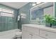 Remodeled bathroom with white vanity, tiled tub, bright lighting, and green accent wall at 4931 Pelican Dr, New Port Richey, FL 34652