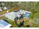 Aerial view of a green home with a pool, large lot, mature landscaping, and a gray roof at 5657 Oceanic Rd, Holiday, FL 34690