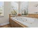 Bright bathroom featuring a tub under windows and tiled surround with a pebble floor at 5657 Oceanic Rd, Holiday, FL 34690