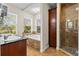 Bright bathroom featuring a tub under windows, shower with pebble floor, and a granite vanity at 5657 Oceanic Rd, Holiday, FL 34690