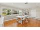 Dining room with hardwood floors, white table, chairs, and natural light from the windows at 5657 Oceanic Rd, Holiday, FL 34690
