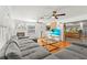 Bright living room with hardwood floors, fireplace, ceiling fans, and large gray sofa at 5657 Oceanic Rd, Holiday, FL 34690