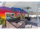 Outdoor seating on a covered patio with a colorful mural, a ceiling fan, and travertine flooring at 5657 Oceanic Rd, Holiday, FL 34690