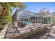 Enclosed pool with a screened-in enclosure, wooden deck, and lush greenery at 5657 Oceanic Rd, Holiday, FL 34690