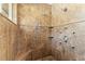 Tile shower featuring multiple shower heads, stone flooring, and built-in tiled corner shelves at 5657 Oceanic Rd, Holiday, FL 34690