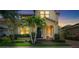 Charming two-story home featuring a manicured lawn and lush landscaping with palm trees at dusk at 6113 Yeats Manor Dr, Tampa, FL 33616