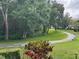 Green backyard with trees, a curved path, and a park bench at 1258 Pine Ridge W Cir # F1, Tarpon Springs, FL 34688