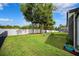 Large backyard features lush lawn, mature trees, and a white fence for added privacy at 13523 Meadow Golf Ave, Hudson, FL 34669