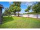 Spacious backyard with green grass, mature trees, and a white fence creates a private oasis at 13523 Meadow Golf Ave, Hudson, FL 34669