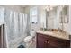 Well-lit bathroom features a granite vanity, large mirror, and shower with a blue patterned curtain at 13523 Meadow Golf Ave, Hudson, FL 34669
