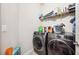 Functional laundry room with front load washer and dryer, and shelving for storage at 13523 Meadow Golf Ave, Hudson, FL 34669