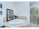 A bright bathroom featuring an oval soaking tub, glass-enclosed shower, and tiled floors at 1411 Tessano Pl, Palm Harbor, FL 34683