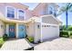 Home featuring a two-car garage, blue front door with a sunflower wreath, and a brick paved driveway at 1411 Tessano Pl, Palm Harbor, FL 34683