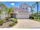Charming two-story home featuring a two-car garage, tropical landscaping, and a welcoming blue front door at 1411 Tessano Pl, Palm Harbor, FL 34683