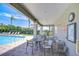 Shaded poolside patio with tables, chairs, and a view of the sparkling community pool and surrounding greenery at 1411 Tessano Pl, Palm Harbor, FL 34683