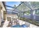 Inviting screened patio with tiled floor, comfortable seating, and a tranquil outdoor dining area at 1411 Tessano Pl, Palm Harbor, FL 34683