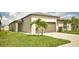 Beige single-story home featuring a two-car garage, palm trees, and a well-manicured lawn at 16623 Carlton Pond St, Wimauma, FL 33598