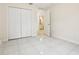 Bright bedroom featuring white tile flooring and a double-door closet, with a bathroom visible through the doorway at 212 W Humphrey St, Tampa, FL 33604