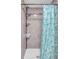 Tiled shower with corner shelves and a shower head with a blue shower curtain at 2419 Wishing Well Way, Tampa, FL 33619