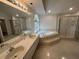 Well-lit bathroom with a tub, walk-in shower with glass door, dual sinks, and plenty of counter space at 2635 Jarvis Cir, Palm Harbor, FL 34683