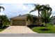 Charming home with a brick driveway, two-car garage, and well-kept lawn with palm trees and garden beds at 29435 Snap Hook Dr, San Antonio, FL 33576