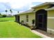 Home's exterior showcasing a screened door, manicured lawn, and decorative landscaping with lush plants and mulch at 29435 Snap Hook Dr, San Antonio, FL 33576
