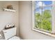 Powder room features toilet, toilet paper holder, shelf, and exterior view at 3484 Primrose Way, Palm Harbor, FL 34683
