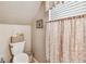 Cozy bathroom with toilet, decorative accents, and window with leaf-patterned curtain at 3484 Primrose Way, Palm Harbor, FL 34683