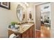 Elegant bathroom vanity with granite countertop, round mirror, and access to a living space at 3484 Primrose Way, Palm Harbor, FL 34683