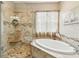Bathroom featuring glass enclosed shower, soaking tub, and tile surround at 3484 Primrose Way, Palm Harbor, FL 34683