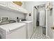 Functional laundry room with washer, dryer, overhead storage and tile flooring at 3484 Primrose Way, Palm Harbor, FL 34683