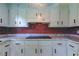 Bright kitchen featuring white cabinets, red backsplash, and marble countertops at 38320 14Th Ave, Zephyrhills, FL 33542