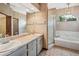 Bathroom featuring double sinks, large mirror, shower and a garden tub with window at 4744 Burlington Rd, Land O Lakes, FL 34639