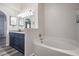 Modern bathroom with navy blue double sink vanity, granite countertop, and a pristine white soaking tub at 5334 Tummel Ct, Wesley Chapel, FL 33545